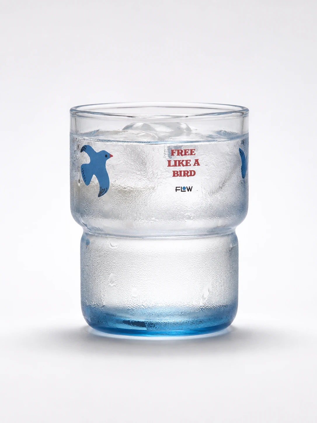blue-tinted stackable glass tumbler with a stepped waist and a flying-bird motif, holding ice water