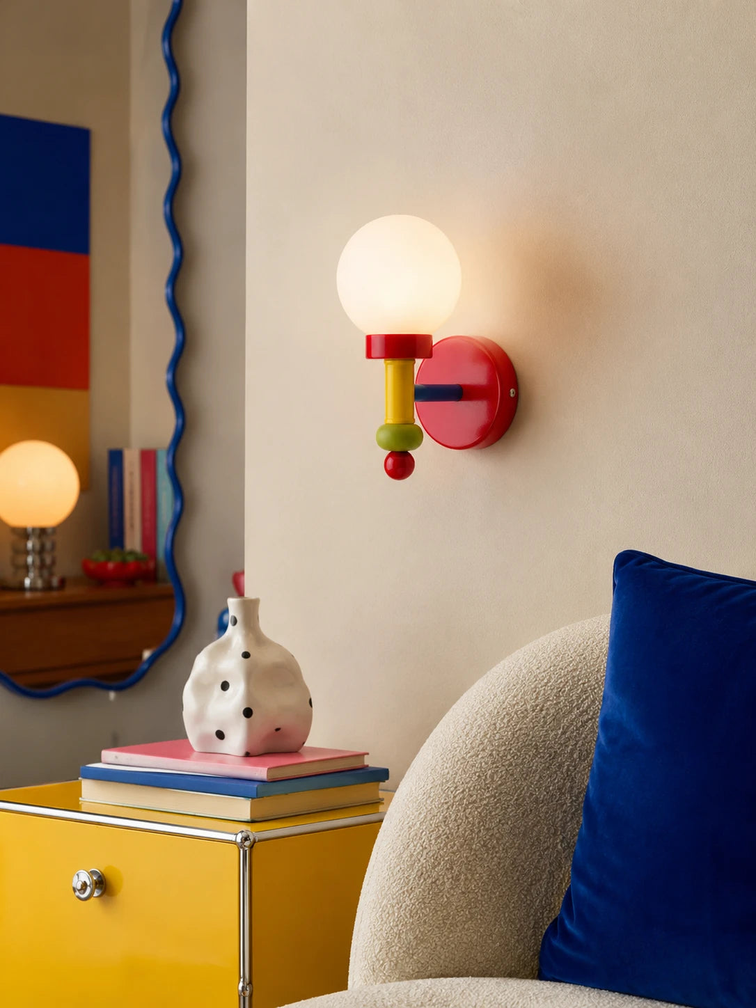 Memphis color-blocked wall lamp glowing beside a yellow cabinet and boucle chair