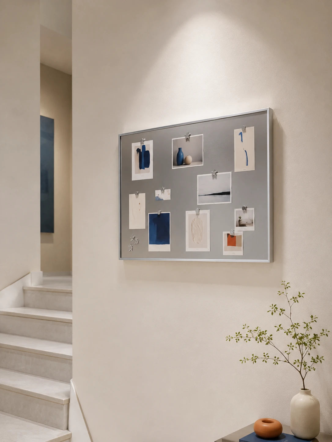 silver magnetic board on a stairway wall holding art cards with small star magnets