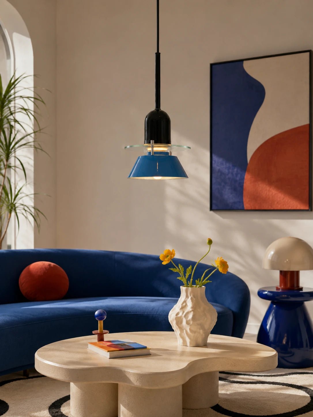 blue disc-and-cone pendant light above a cream flower-shaped coffee table and blue curved sofa