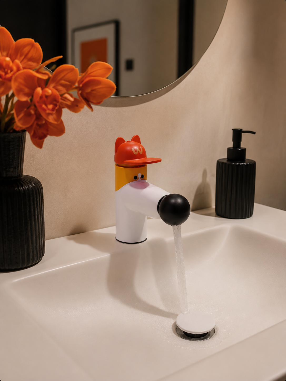 cartoon dog basin faucet with red cap pouring water near a black soap dispenser and orange orchids