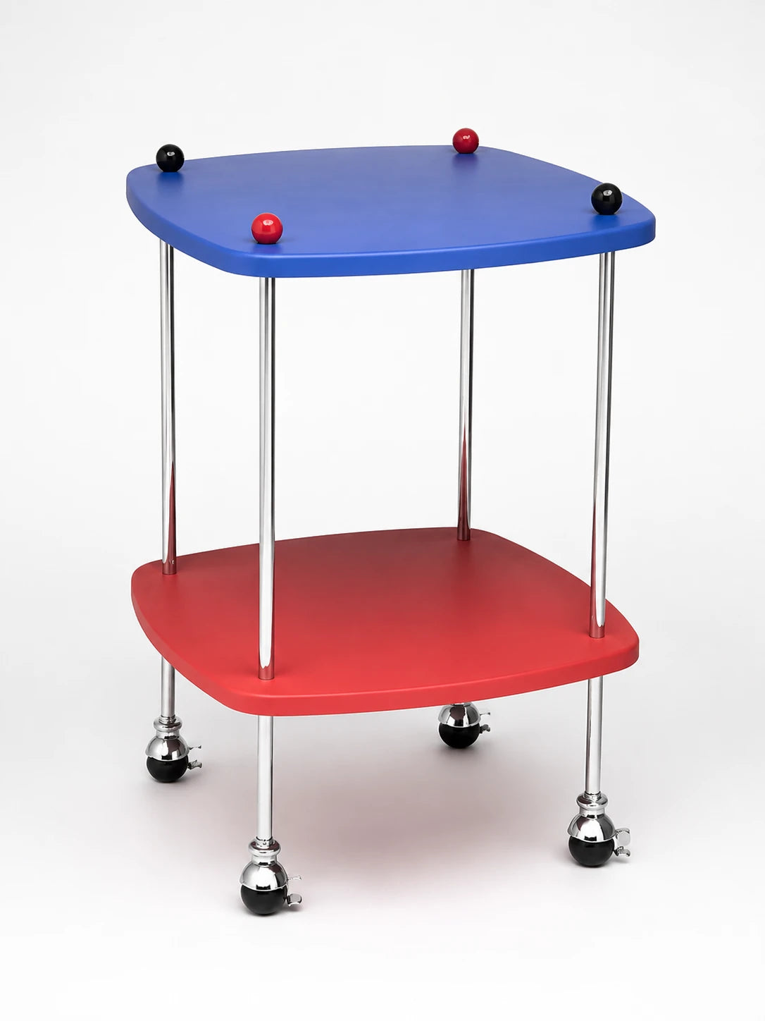 two-tier side table with a cobalt blue top and red lower shelf on chrome legs with ball casters