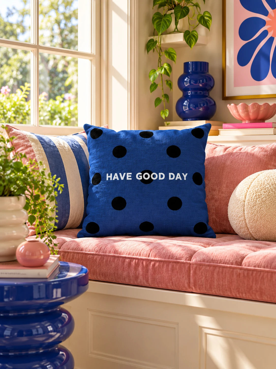 navy polka dot slogan pillow on a pink window seat with an open book