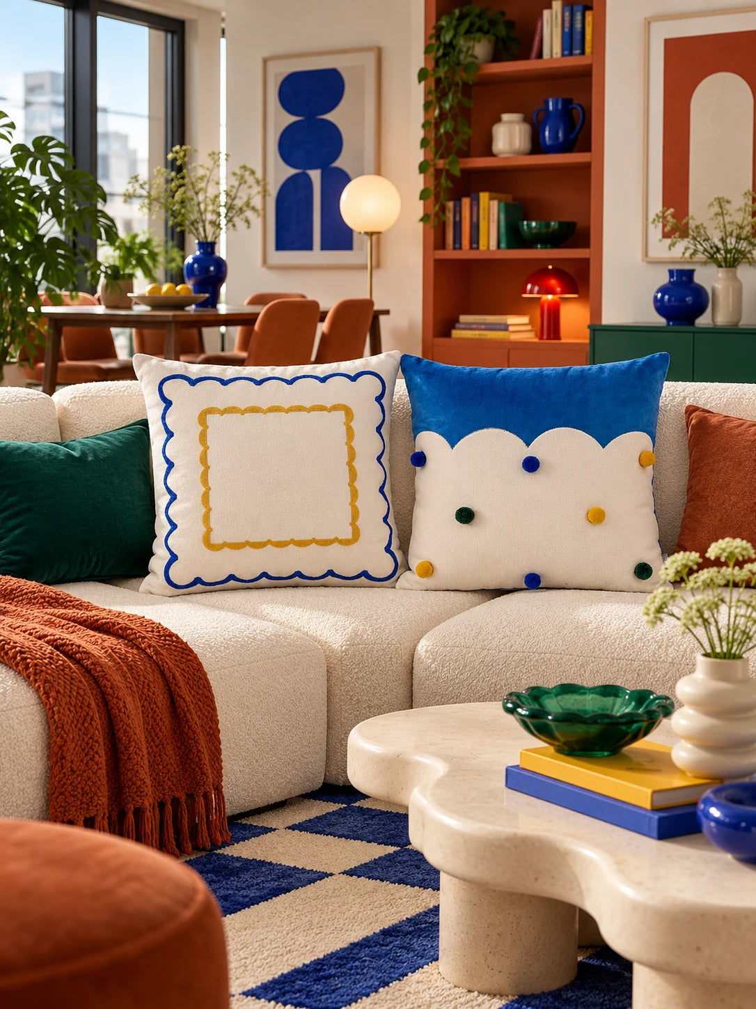 Double scallop and cloud-edge pillows on a cream sectional with a rust throw and a blue checkered rug