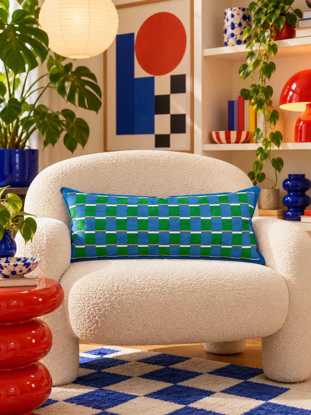 Blue and green check lumbar pillow on a cream boucle armchair over a cobalt checkerboard rug