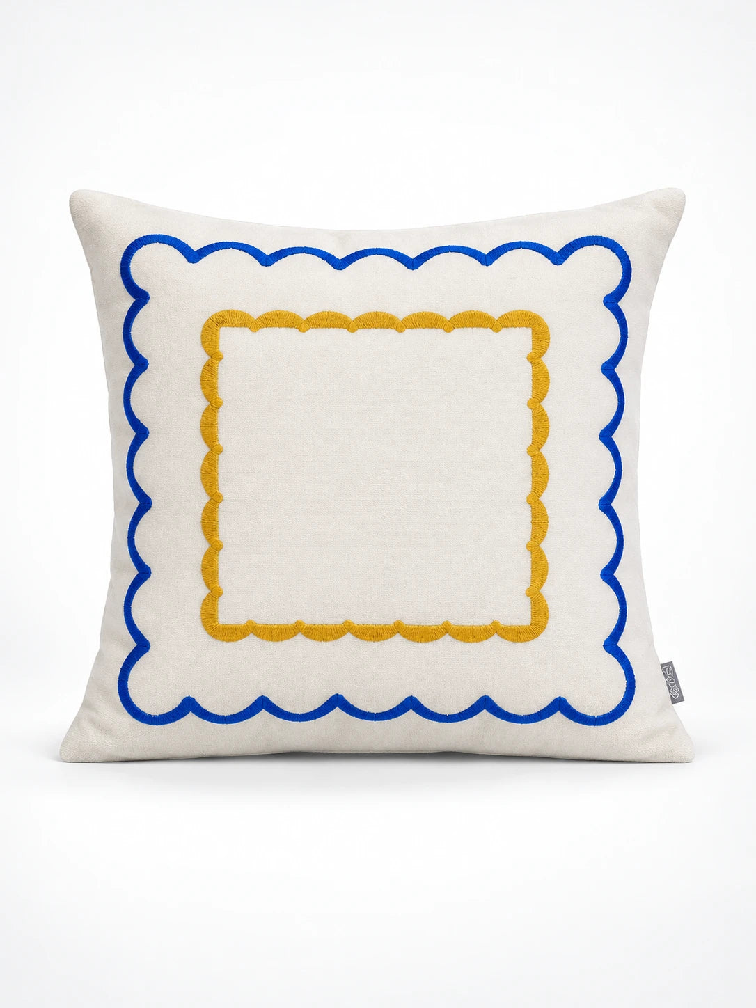Cream throw pillow with a cobalt scalloped border and an inner mustard scalloped square, studio shot