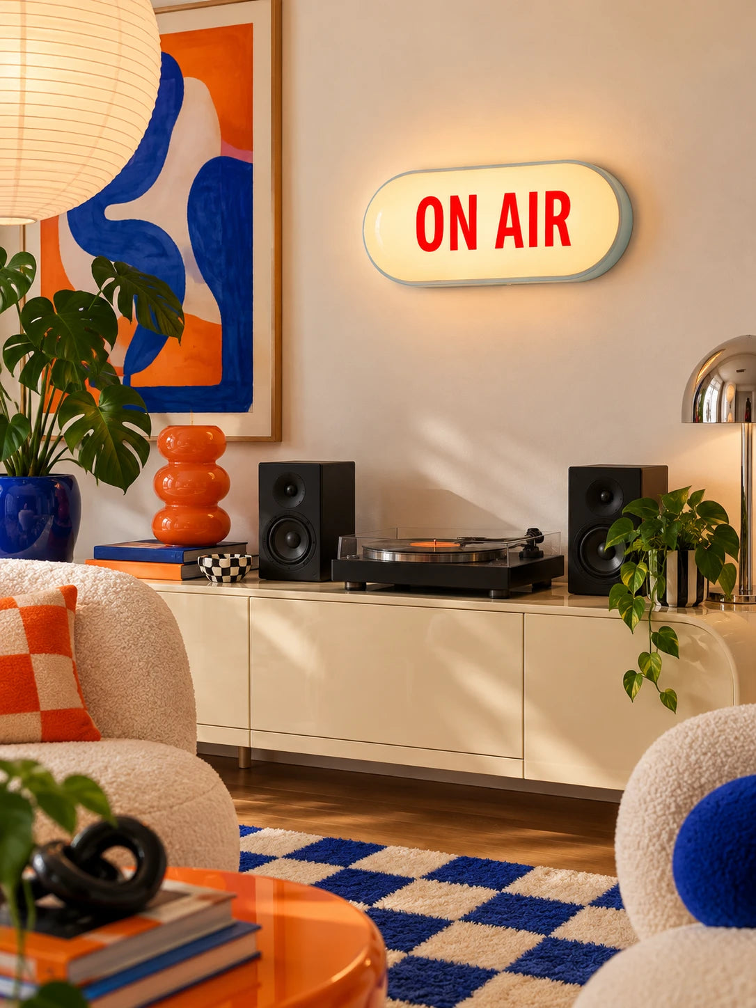 ON AIR sign mounted above a record player console with speakers and blue checkered rug