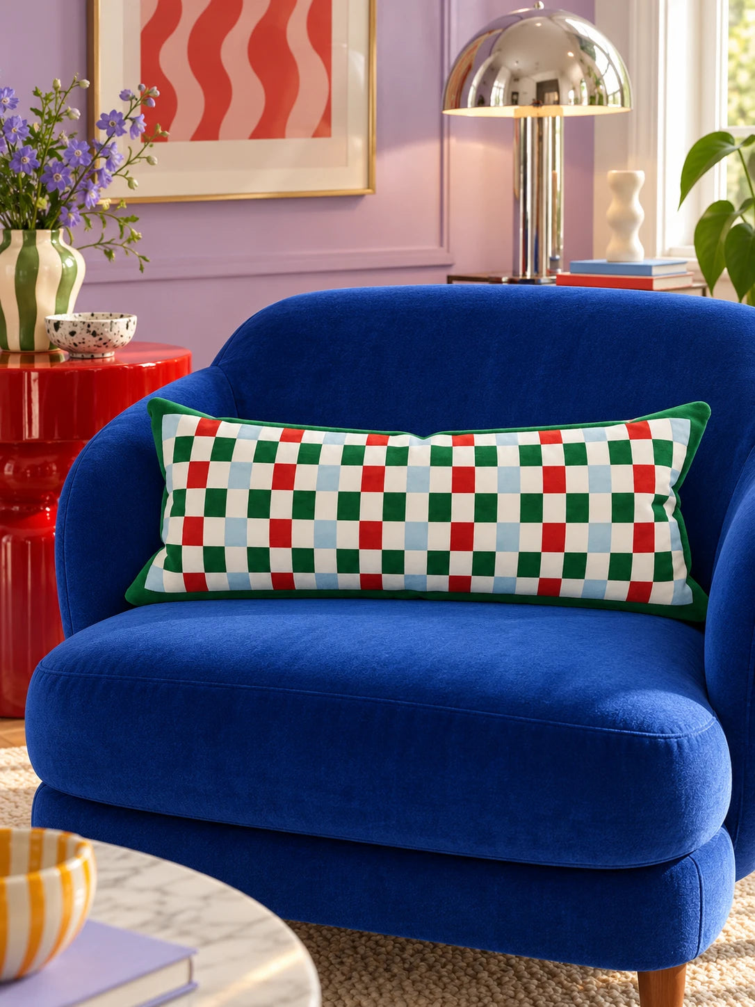 Red and green checkerboard lumbar pillow on a cobalt velvet loveseat in a lilac room
