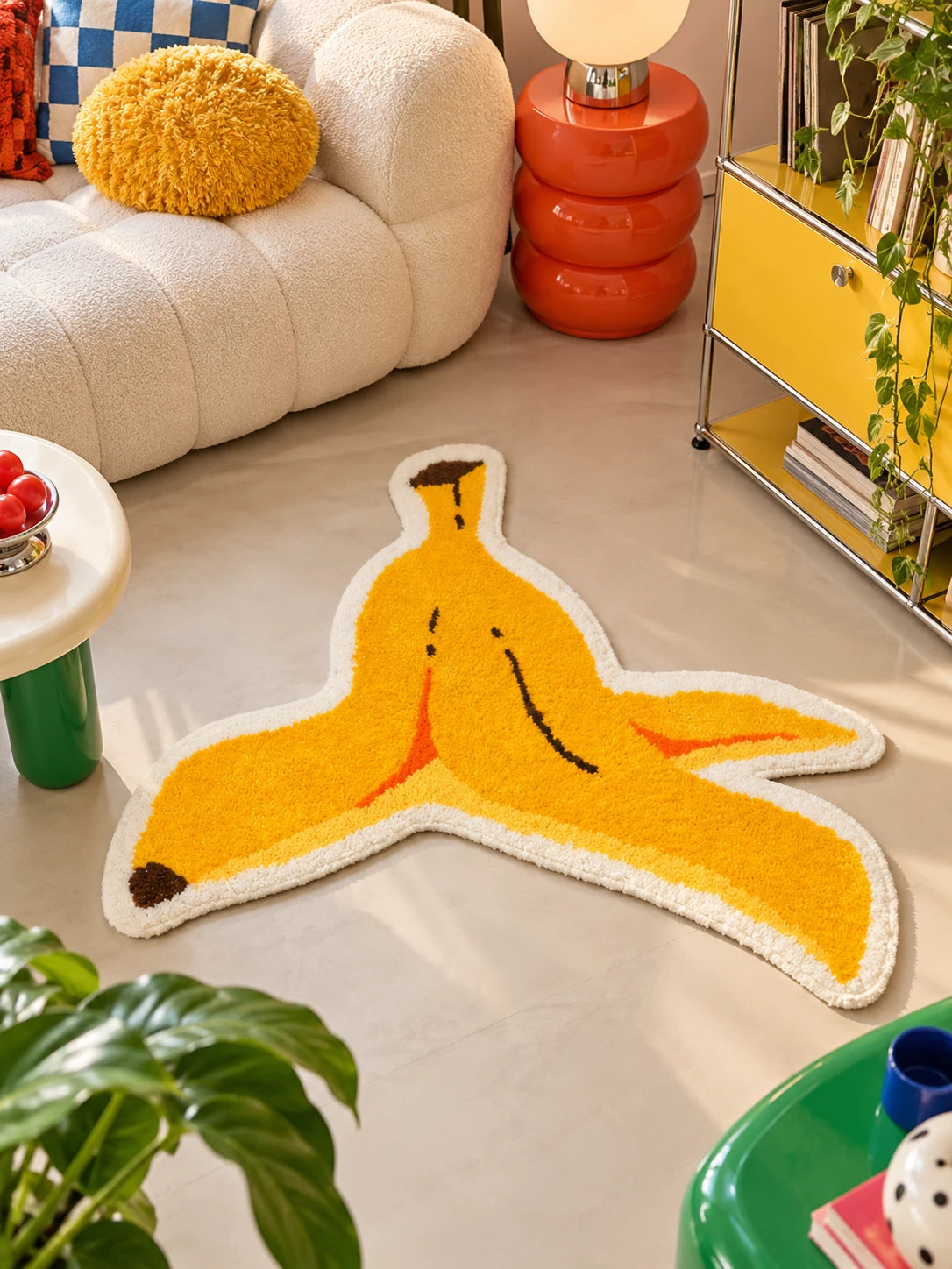 Plush banana peel mat near a boucle sofa with fuzzy yellow pillow and red side table