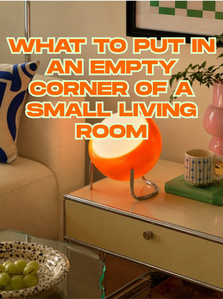 Orange glass orb table lamp glowing warm on a side table in a living room corner beside an armchair, a mug and a plant