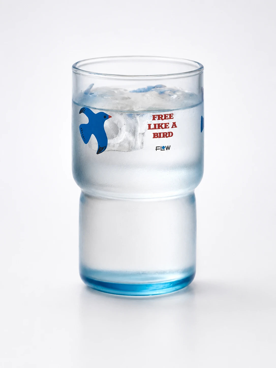tall blue-tinted glass tumbler with a flying-bird motif and a narrower stepped base, filled with ice water