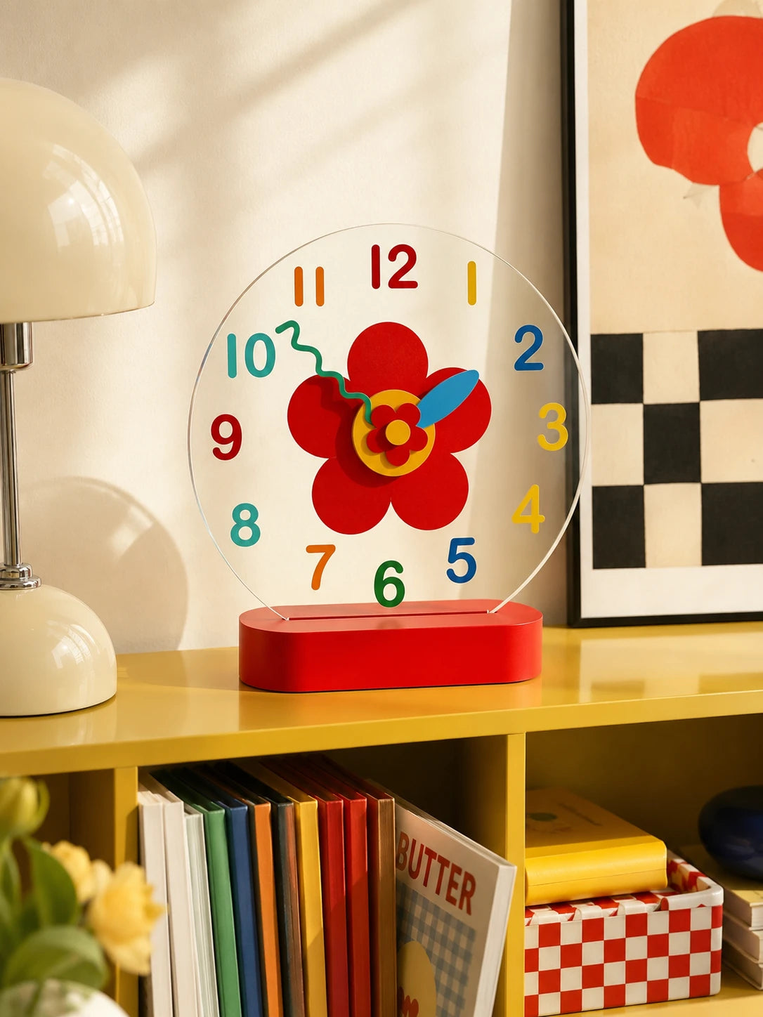 flower face silent clock styled on a yellow shelf beside a cream mushroom lamp and framed art