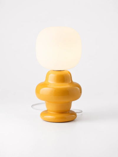 mustard yellow ceramic table lamp with a rounded square frosted glass shade on white background
