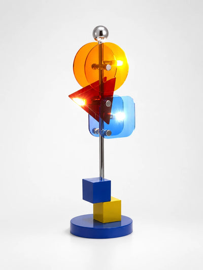 Memphis table lamp with lit amber disc, red triangle and blue square acrylic panels on a chrome stem