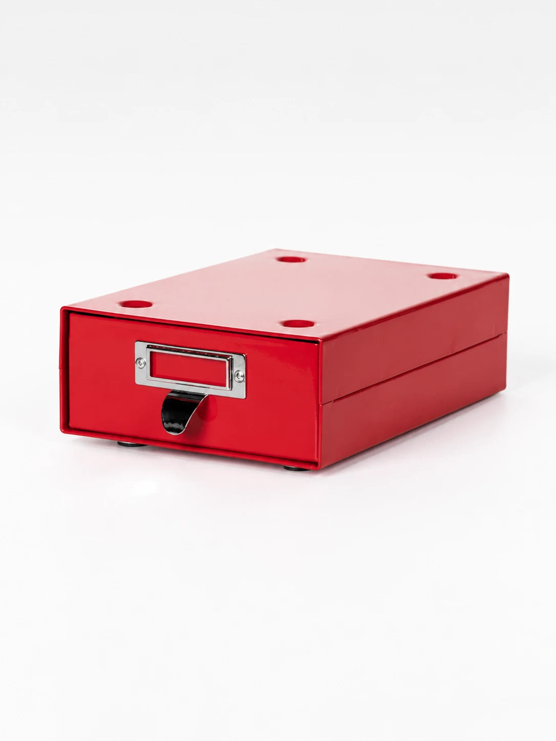 red powder-coated steel storage drawer with chrome label frame, angled studio view