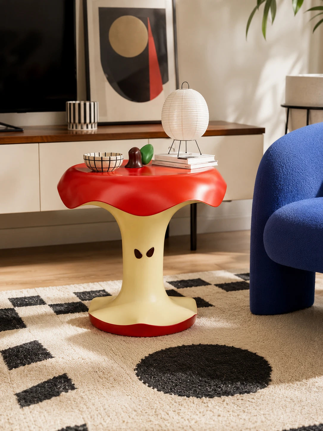 apple core accent table in a living room with paper lantern lamp, books and blue boucle chair