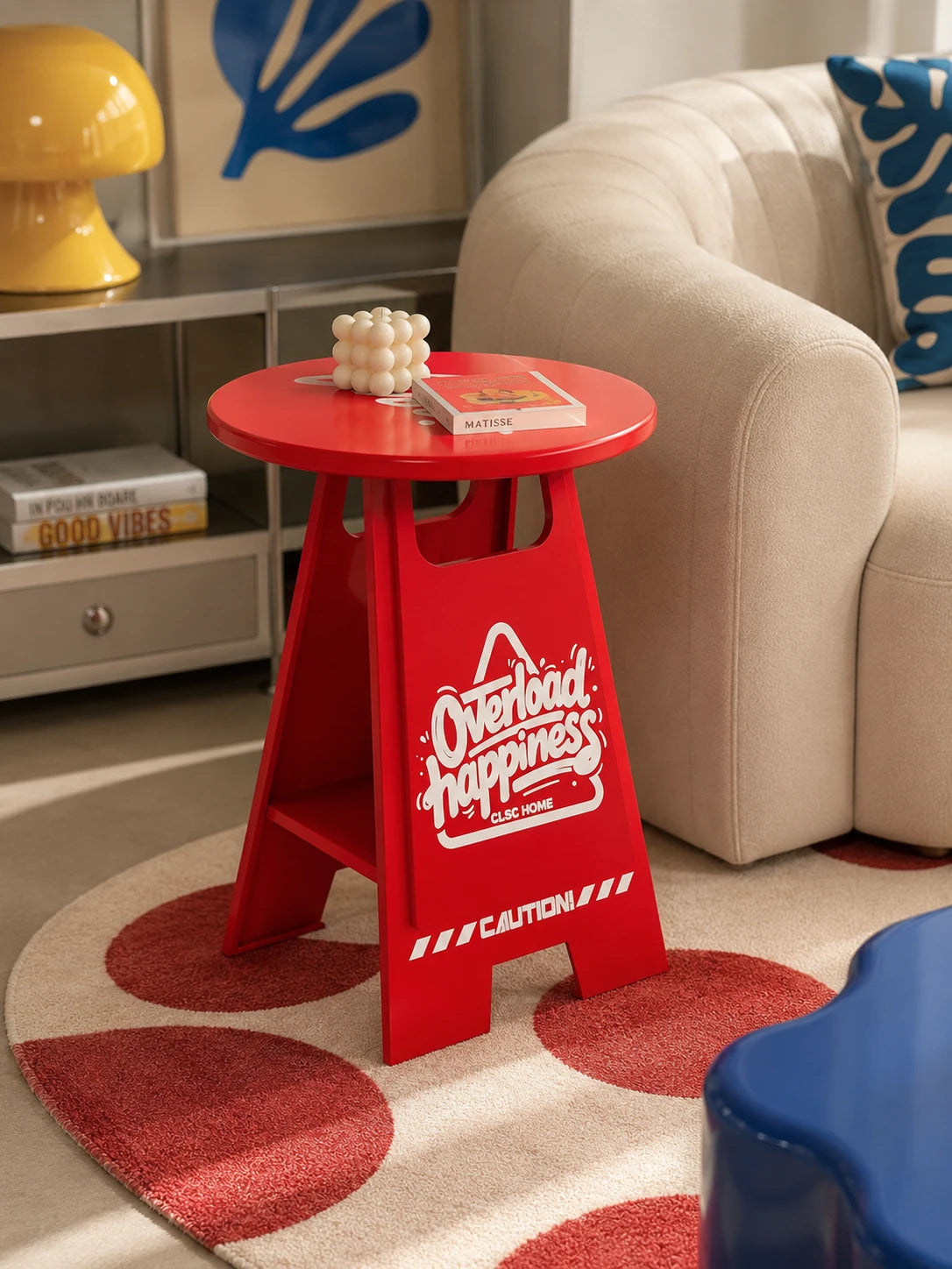 red caution-sign side table styled beside a cream boucle sofa with a bubble candle and book on its round top