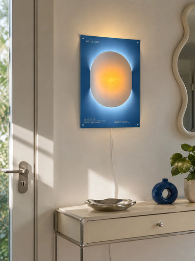 poster night light mounted by a front door glowing warm orange above a silver dish and plant