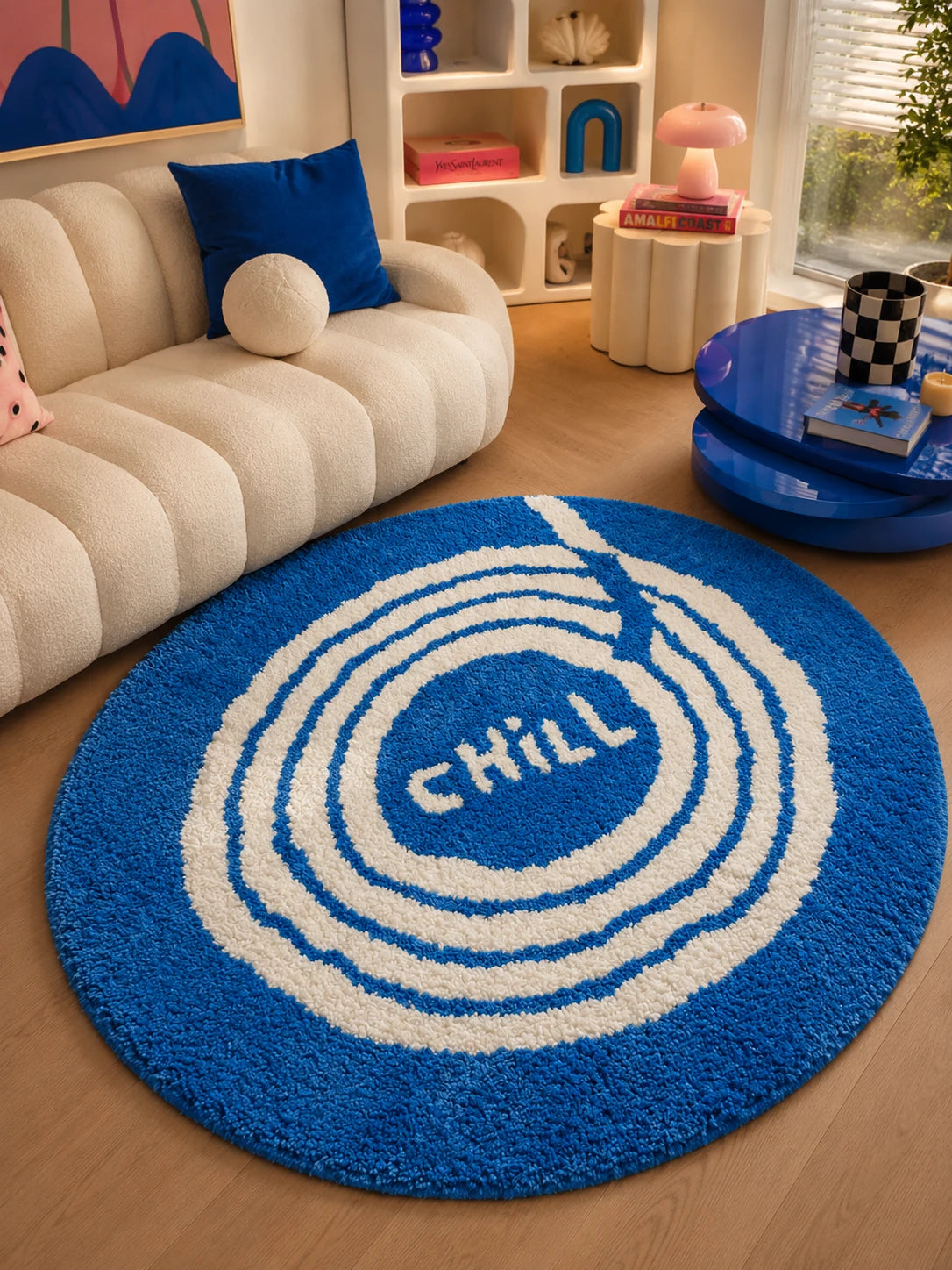 blue vinyl record rug on a wood floor beside a cream boucle sofa and glossy blue coffee table