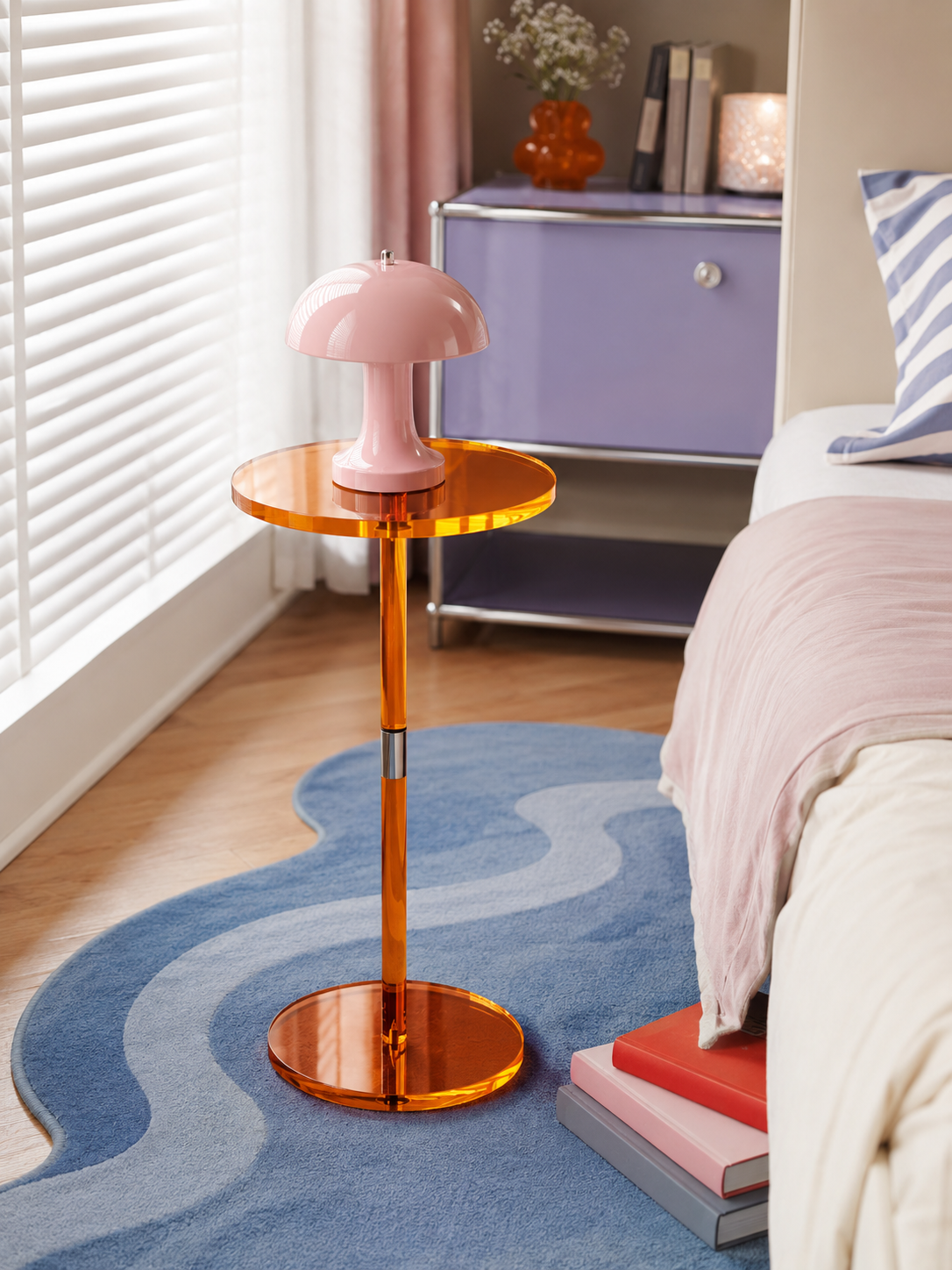 orange acrylic pedestal side table with a pink mushroom lamp on a blue wavy rug beside a bed