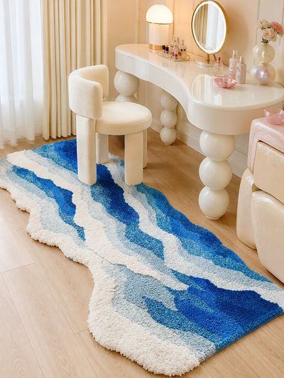 ocean wave plush rug on wood floor beside a cream vanity chair and white dressing table