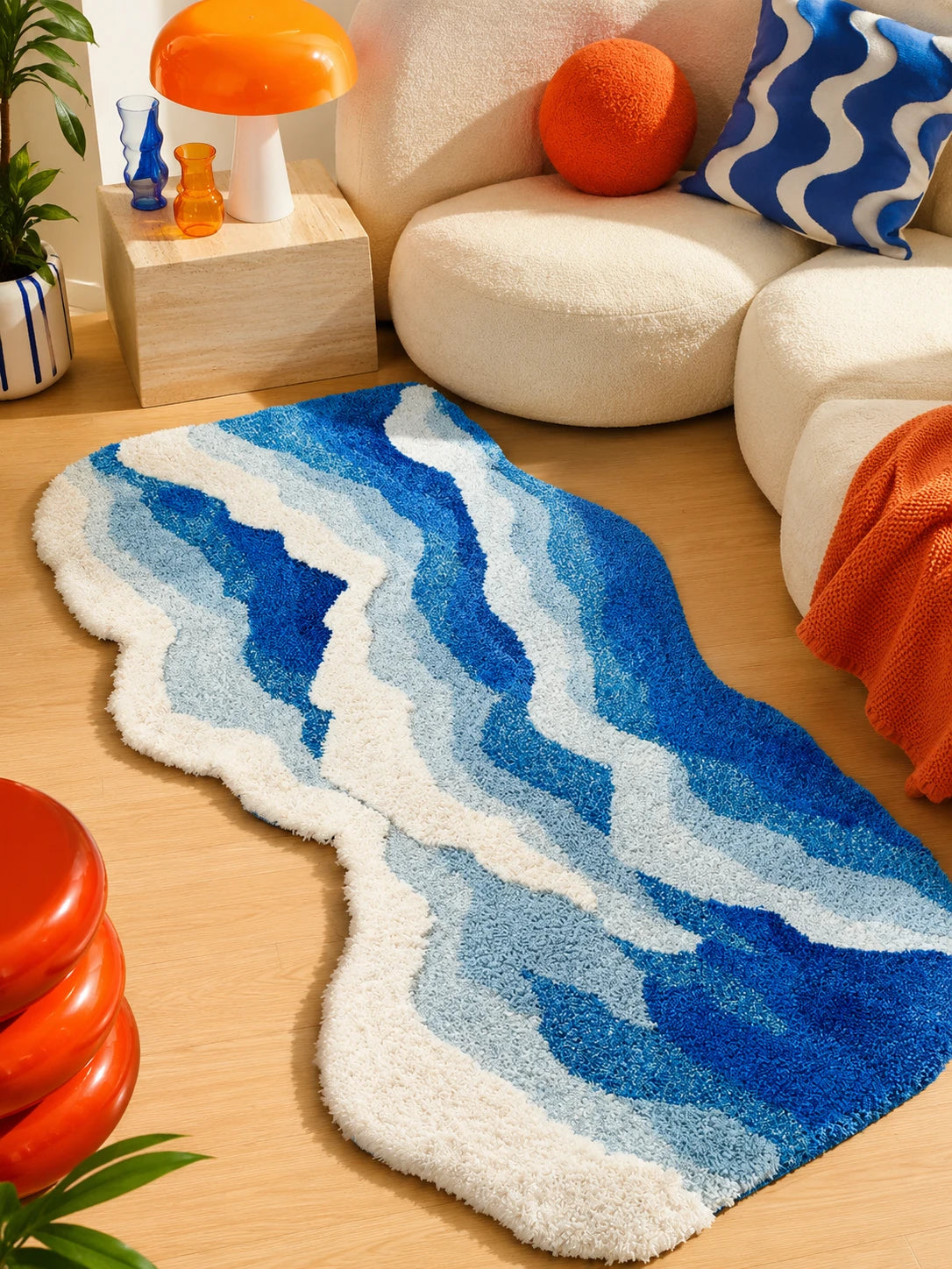 scalloped blue wave rug in a living room beside a cream boucle sofa with an orange throw