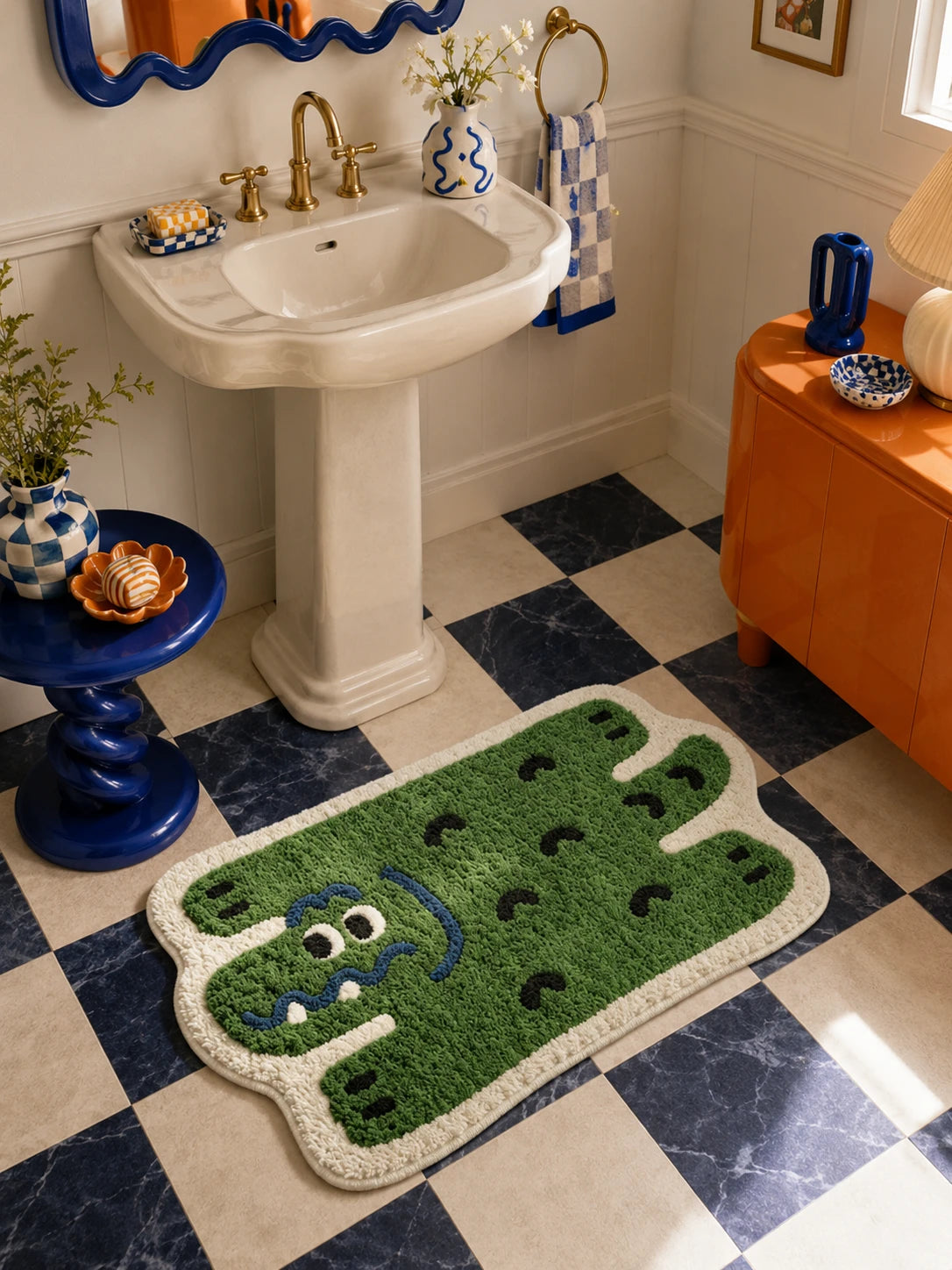 green alligator bath mat on navy and cream checkerboard tile beside a pedestal sink