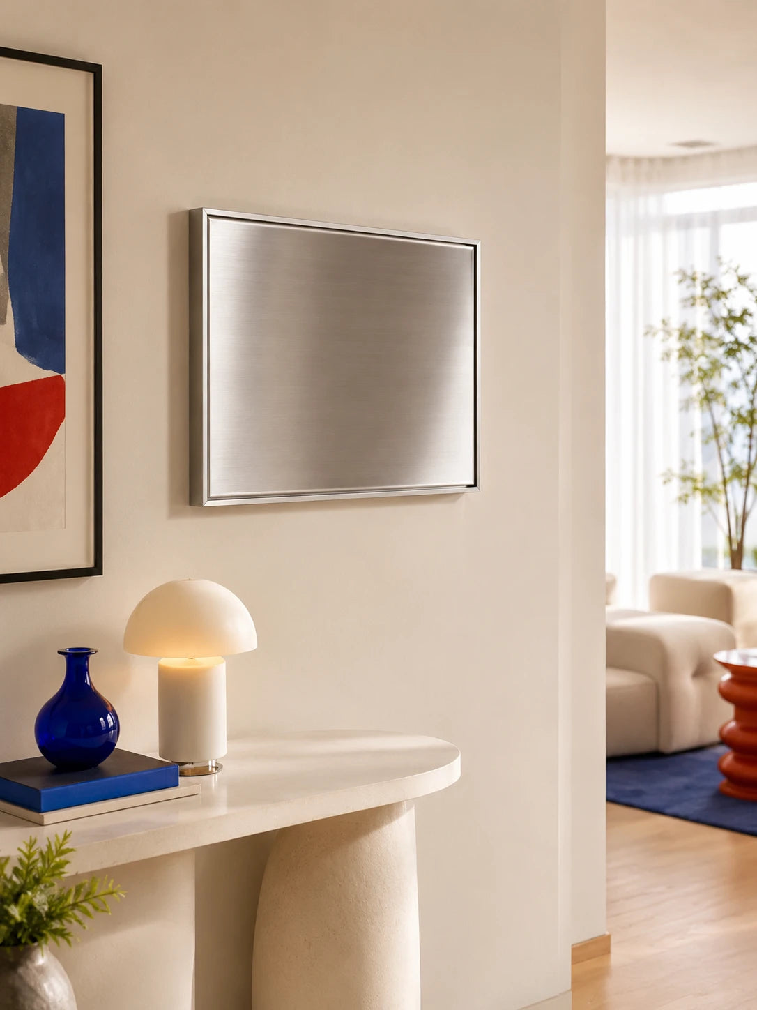 blank brushed steel magnetic wall panel in a silver frame above a cream console with a mushroom lamp