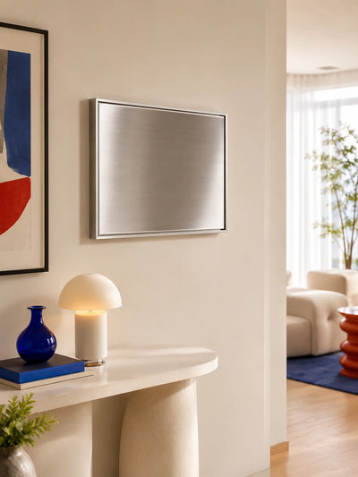 blank brushed steel magnetic wall panel in a silver frame above a cream console with a mushroom lamp