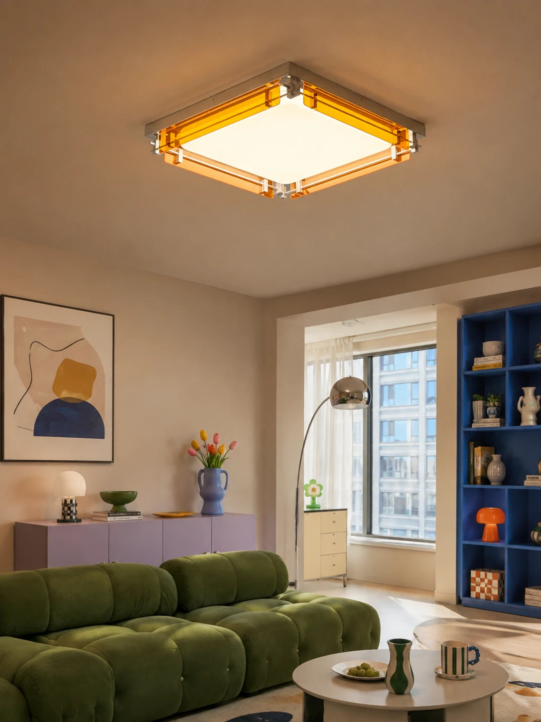 square amber ceiling light on a low ceiling above a green tufted sofa and blue shelving