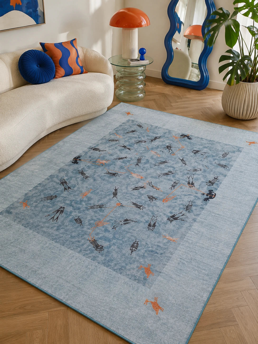 blue folk fishing scene rug under a cream boucle sofa with cobalt and orange pillows