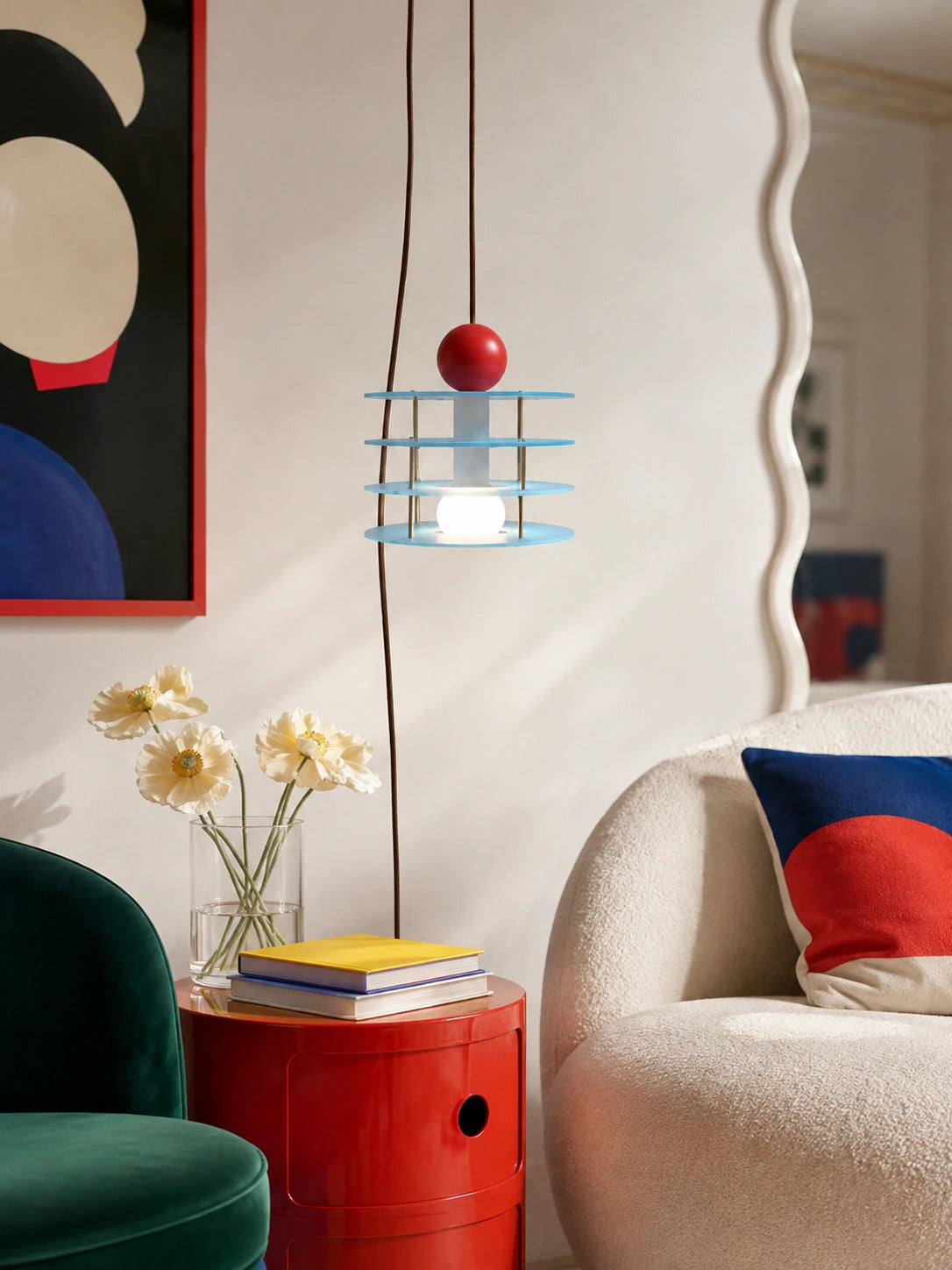blue layered disc pendant hanging over a red storage side table beside a cream boucle sofa
