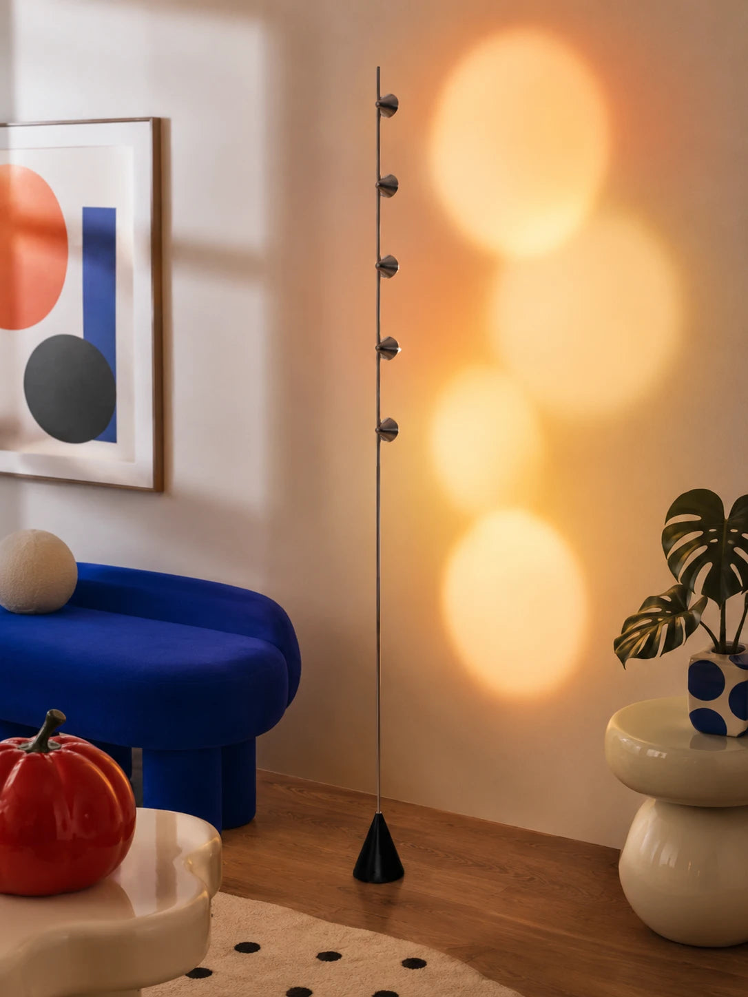 sunset projection floor lamp casting warm orange light circles on a wall beside a cobalt blue bench