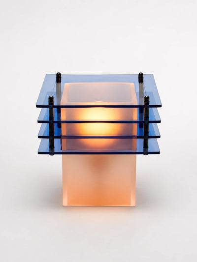 ocean blue acrylic table lamp with four tinted square tiers glowing warm around a frosted base