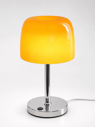 Amber orange glass mushroom table lamp glowing warm on a chrome stem with an on-base switch