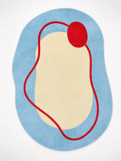 irregular blob-shaped rug with sky blue field, cream center, and red squiggle line ending in a red dot