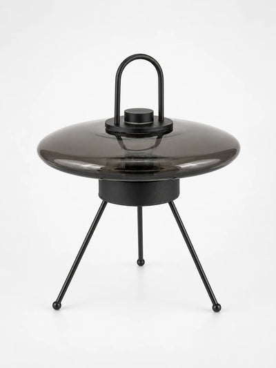 Smoked glass UFO saucer lamp with a black loop handle on a tripod base with ball feet, unlit studio view