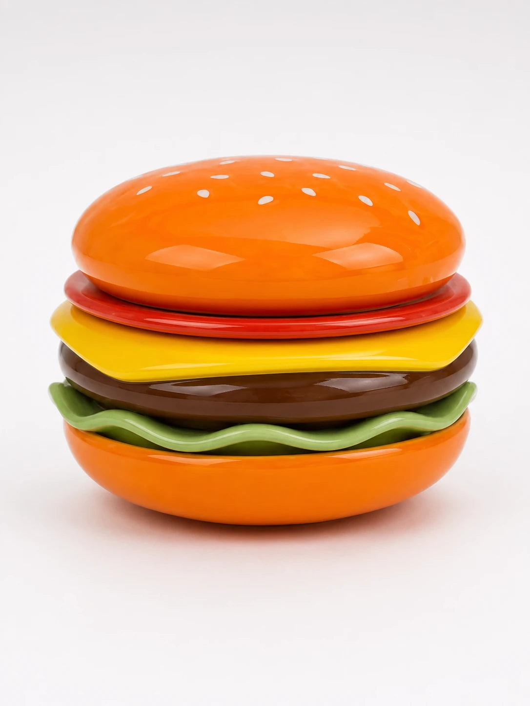 glossy ceramic hamburger stacking plate set assembled with orange sesame bun, tomato, cheese, patty and lettuce layers
