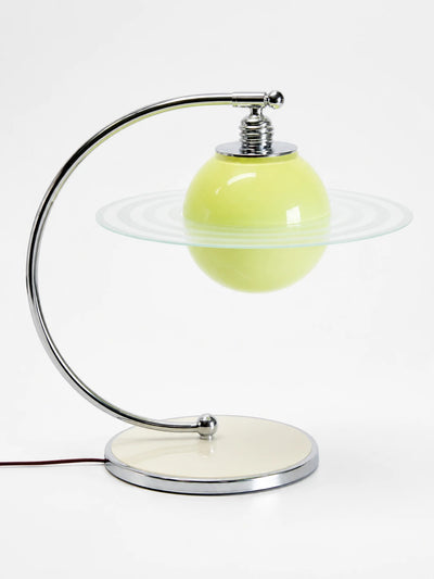 Chartreuse green glass globe table lamp with a clear etched Saturn ring disc on a chrome arc arm and cream base