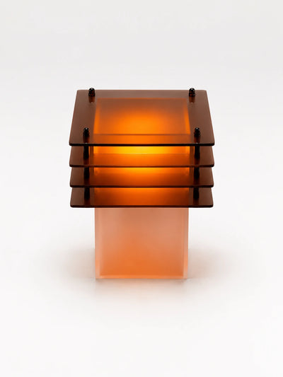 amber-lit tiered acrylic table lamp with four stacked square plates over a glowing frosted column