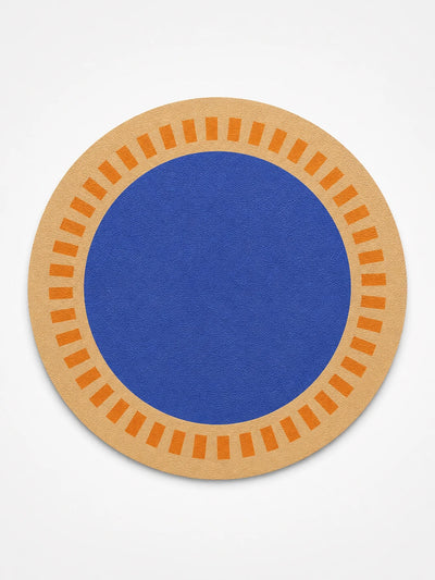 sand-coloured round placemat with orange ticks and a cobalt-blue centre, studio shot