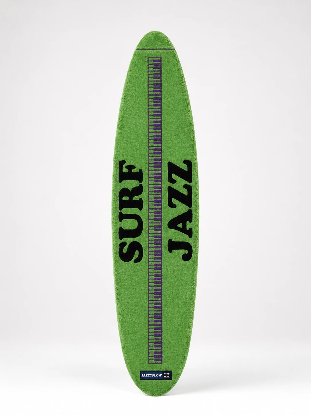 green plush surfboard rug with black lettering and a purple piano-key stripe down the middle