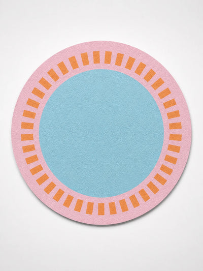 round faux leather placemat with a pink border, orange tick ring and sky-blue centre on a white background