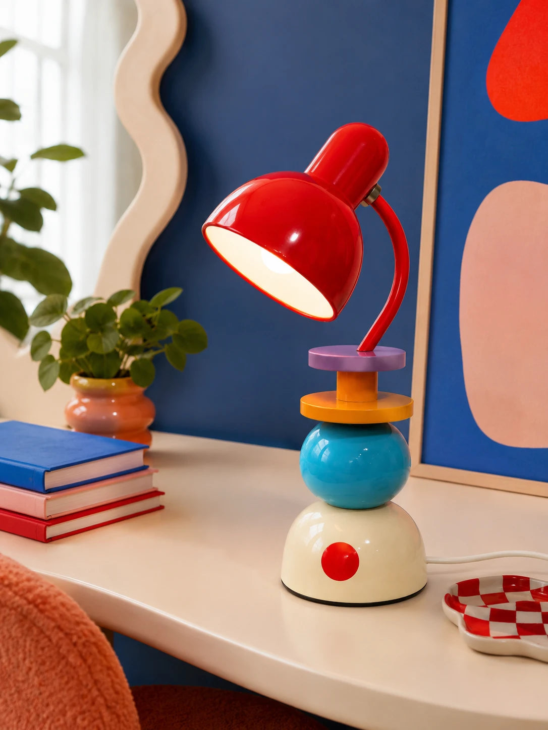 stacked orb Memphis table lamp glowing on a cream desk against a blue wall