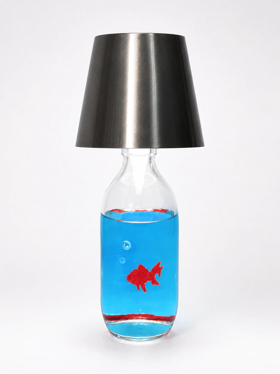 clear glass bottle table lamp with a brushed gunmetal shade and a red goldfish floating in blue liquid