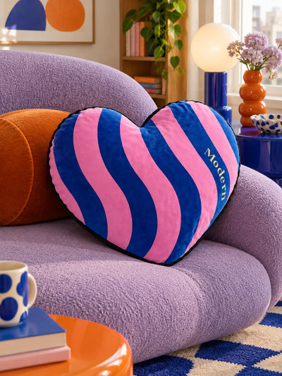 Striped heart pillow in blue and pink on a lilac boucle sofa