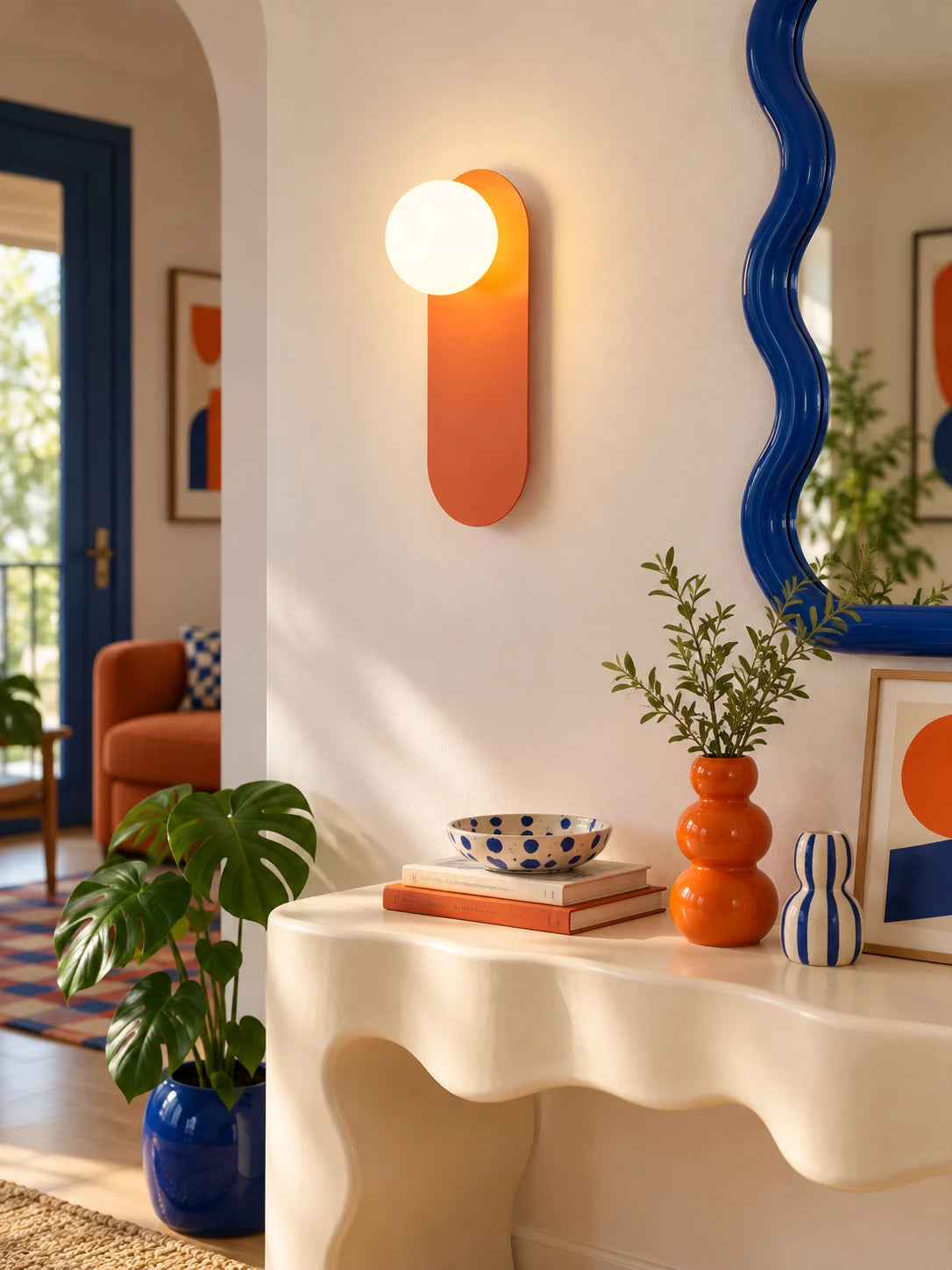 Orange wall lamp above a cream wavy console with a blue wavy mirror