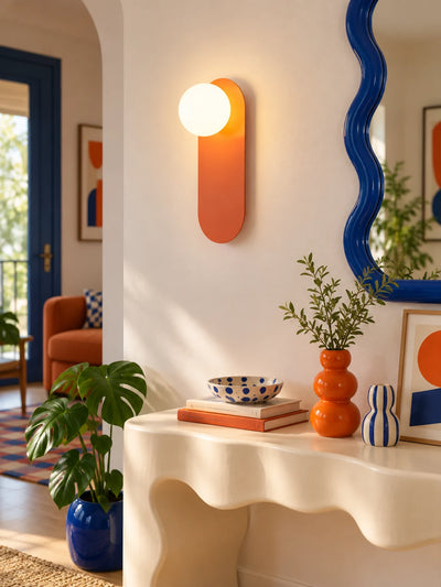 Orange wall lamp above a cream wavy console with a blue wavy mirror