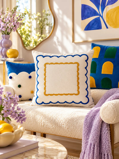 Double scallop throw pillow between cloud-edge and window-arch pillows on a cream sofa with a lilac throw