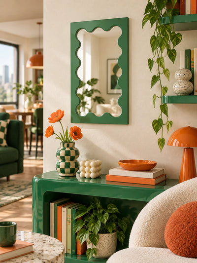 Green wavy-frame vanity mirror in a plant-filled room corner